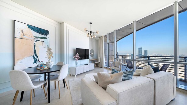 Ein modernes Wohnzimmer mit großem Sofa, Esstisch, Stühlen, einem Flachbildfernseher und einem großen Fenster mit Blick auf die Stadt.