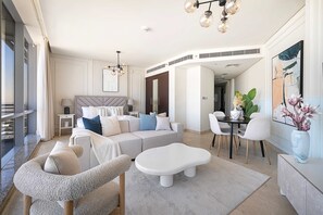 A modern living room with a sofa, a coffee table, and a dining area with chairs. - Silkhaus Chic Studio in Difc Pool Gym (Dubai)