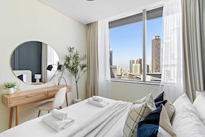 Ein Hotelzimmer mit Bett, Schreibtisch, Spiegel und Fenster mit Blick auf die Stadt.