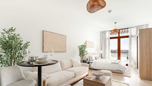 Een moderne hotelkamer met een bank, een eettafel, een bed en een groot raam met uitzicht.
