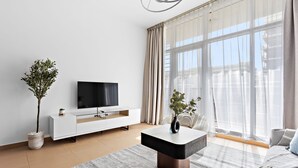 En moderne stue med et hvidt tv-møbel, et fladskærms-tv, et sofabord og en sofa.