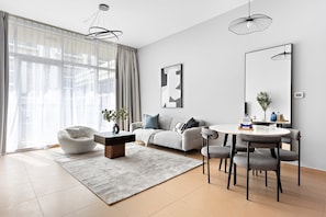 A modern living room with a sofa, armchairs, a coffee table, and a dining table. - Silkhaus Orchid Building Next to Golf Course (Abu Dhabi)
