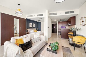 A modern living room with a sofa, coffee table, and a dining area with chairs. - Silkhaus Comfy Studio in Sky Gardens Difc Views (Dubai)