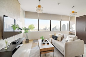 A modern living room with a large TV, a sofa, a coffee table, and large windows with a city view. - Silkhaus Comfy Studio in Sky Gardens Difc Views (Dubai)