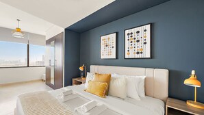 A modern hotel room with a large bed, a nightstand with a lamp, and artwork on the wall. - Silkhaus Comfy Studio in Sky Gardens Difc Views (Dubai)