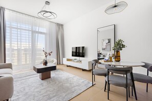 Una sala de estar moderna con un sofá, una mesa de centro, una mesa de comedor con sillas, un televisor y un espejo grande.