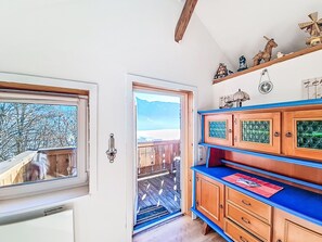 Ein Zimmer mit einem Holzschrank, einem Fenster und einer Tür, die auf einen Balkon im Freien führt.