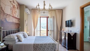 A bedroom with a bed, a dresser, a television, and a view of the sea through a window. - 3Bed-room apartment with mountain view (Castellammare di Stabia)