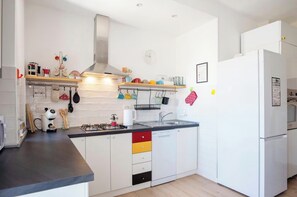 Cocina moderna con armarios blancos, encimera negra, estufa a gas y campana extractora de acero inoxidable.
