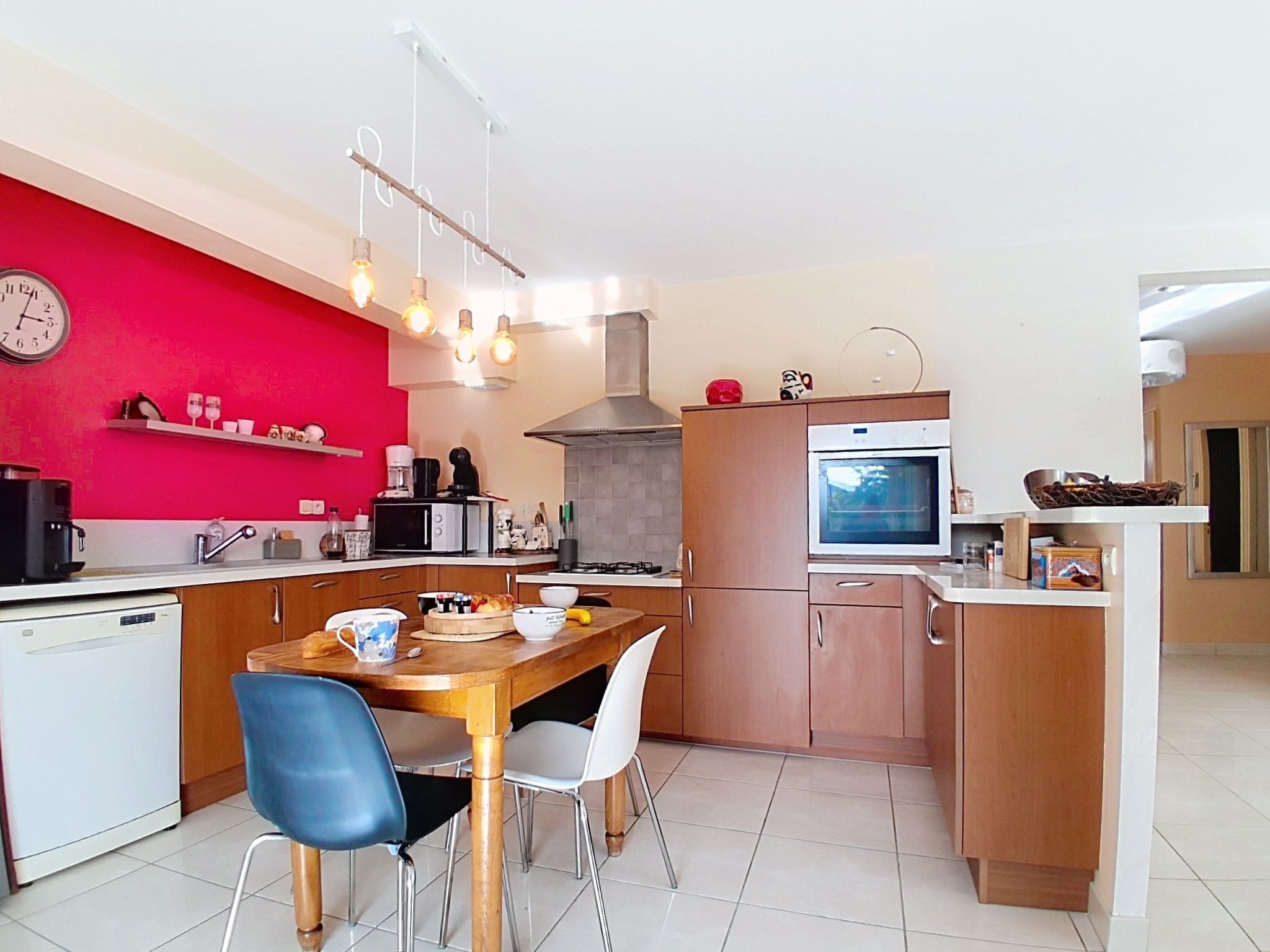 A compact kitchen with a dining area, featuring a microwave, oven, and a clock on the wall.