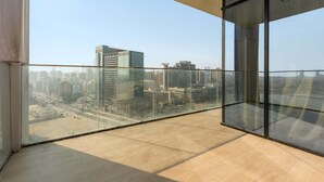 Een hoog gebouw met een glazen balkon met uitzicht op een stadsgezicht.