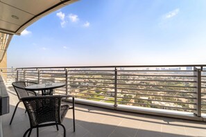 A balcony with two chairs and a table, offering a view of a cityscape. - Silkhaus Exclusive 2bdr in Difc Sky Gardens (Dubai)