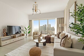 Ein modernes Wohnzimmer mit großem Fenster, einem Flachbildfernseher, einer Couch, einem Couchtisch und einer Zimmerpflanze.