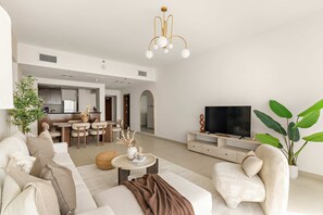 Ein modernes Wohnzimmer mit Sofa, Couchtisch und TV-Schrank. Es gibt einen Essbereich mit Tisch und Stühlen.