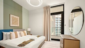 Una habitación de hotel moderna con una cama bien hecha, un tocador, un espejo grande y vistas a la ciudad a través de la ventana.