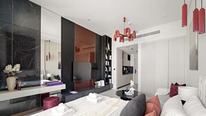 Moderni hotellihuone, jossa on suuri sänky, oleskelualue, televisio ja kylpyhuone, joka näkyy avoimesta ovesta.