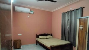Un dormitorio con cama, aire acondicionado, ventilador de techo y armario.