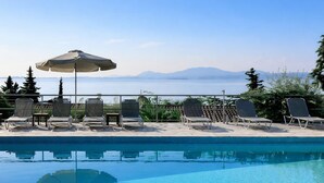 A pool area with lounge chairs and an umbrella, overlooking a body of water and mountains. - Hotel Barbati - Pool & Panoramic Sea View Escape (Corfu)