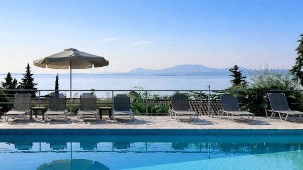 A pool area with lounge chairs and an umbrella, overlooking a body of water and mountains. - Hotel Barbati - Pool & Panoramic Sea View Escape (Corfu)