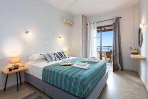 A modern bedroom with a large bed, bedside tables with lamps, a view of the balcony, and a small seating area. - Hotel Barbati - Poolside Gem With Sea Views (Corfu)