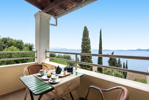 Un balcón con una mesa lista para el té, con vistas a un lago y montañas.