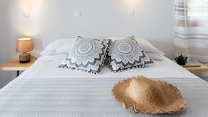 A neatly made bed with patterned pillows, a lamp on a bedside table, and a woven basket on the bed. - Hotel Barbati - Sea & Mountain View Escape (Corfu)