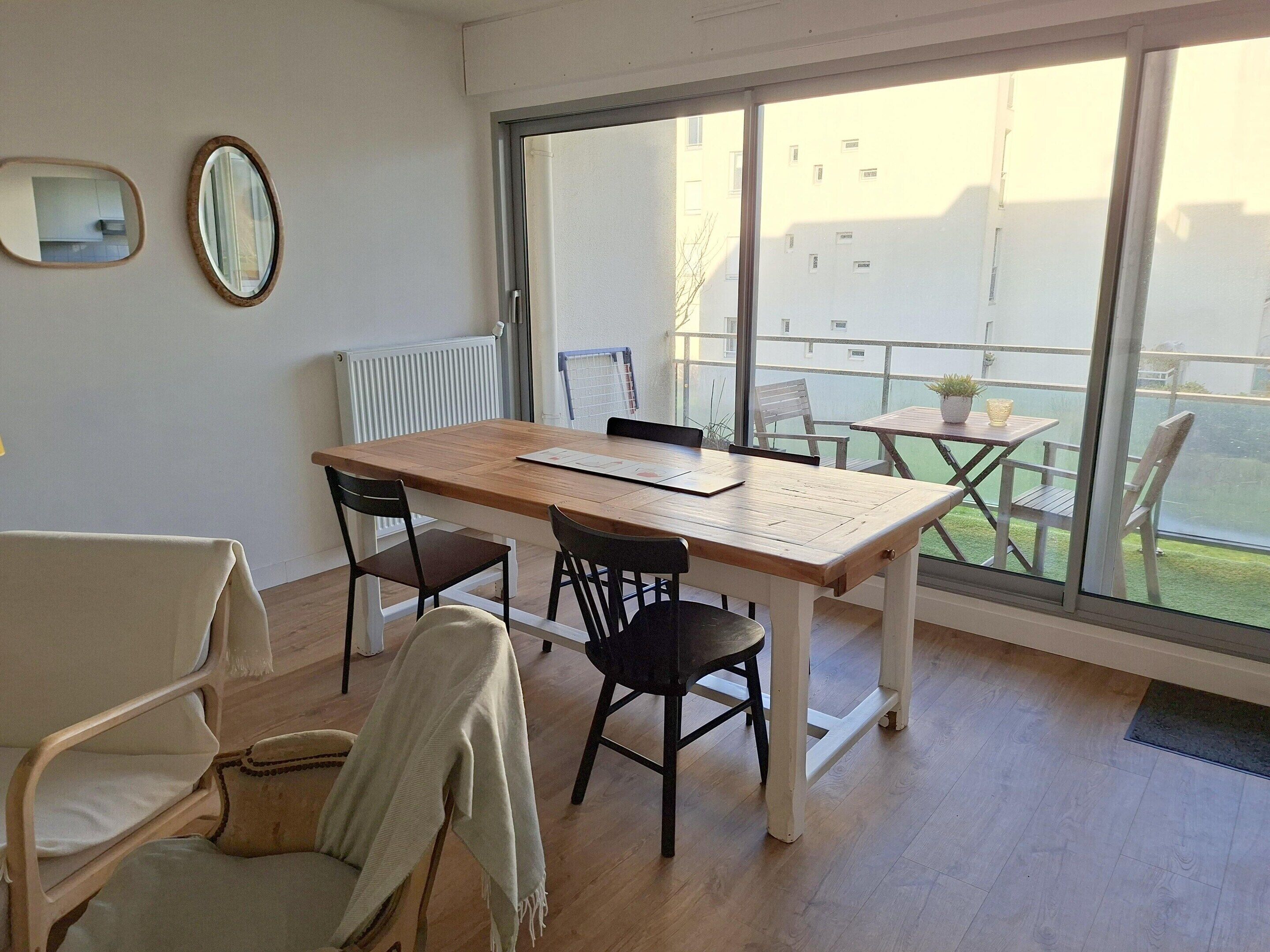 A modern room with a large window, a wooden table, and two chairs.