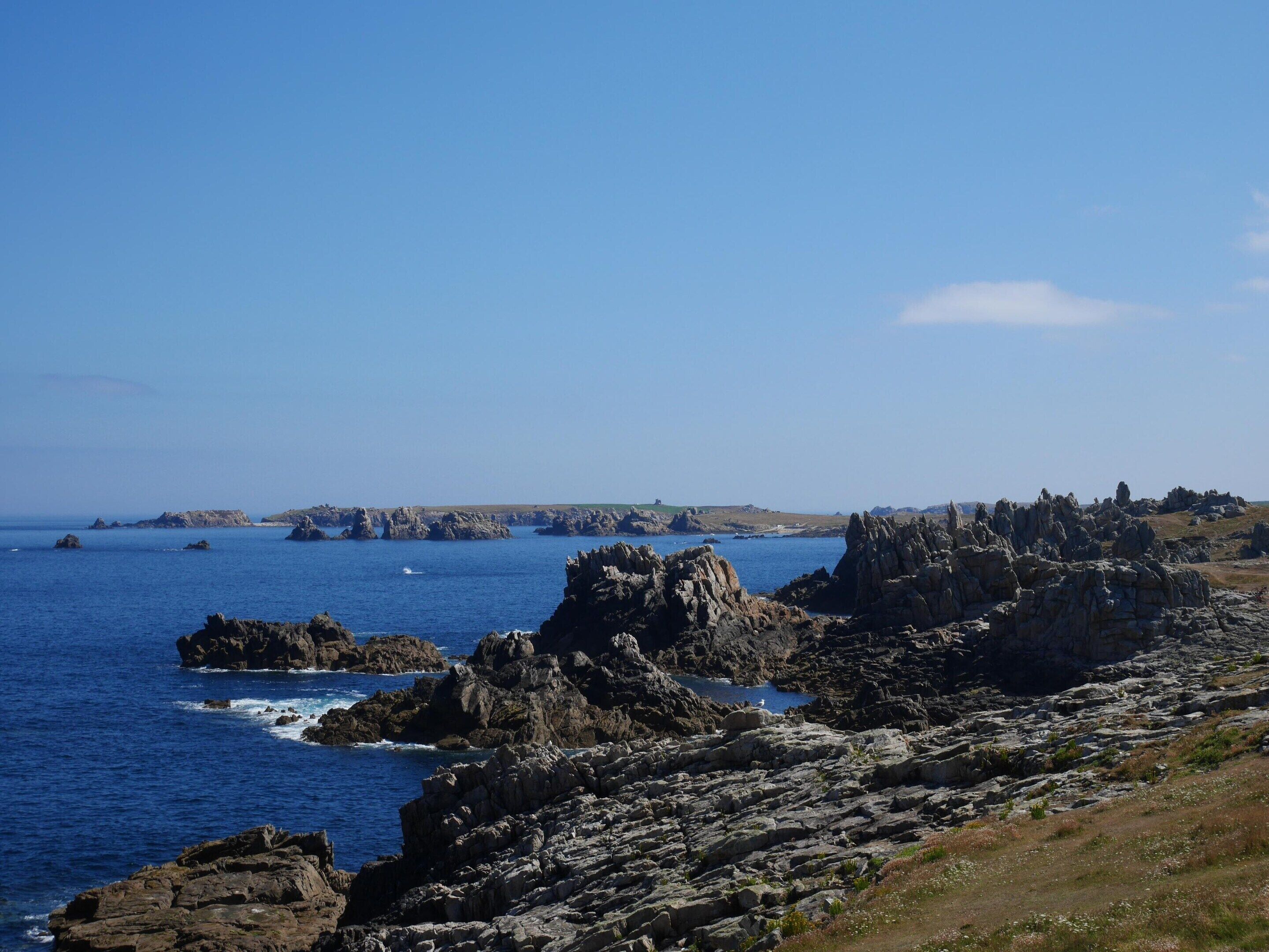 A coastal landscape with rocky terrain and the sea.