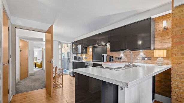 Una cocina moderna con armarios oscuros, una isla grande y una pared de ladrillo decorativa.