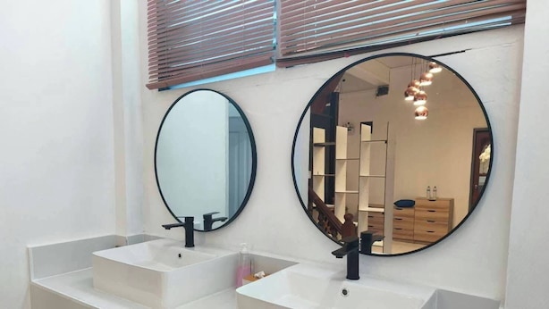Une salle de bain avec deux lavabos blancs, un miroir rond et un meuble-lavabo en bois.