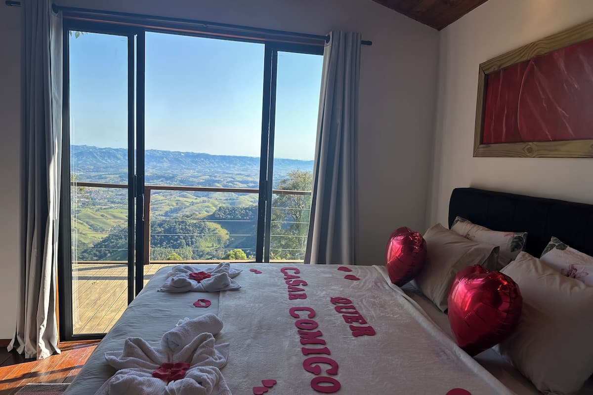 Un dormitorio con un ventanal grande, una cama con toallas y un mensaje, y vistas al campo.
