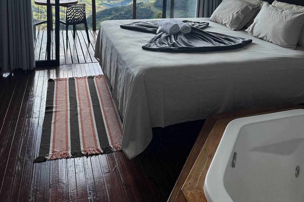 Un dormitorio con una cama grande, vistas al campo y suelo de madera.