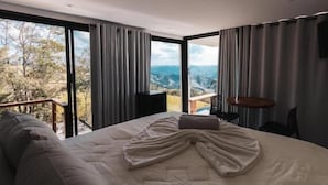 A bedroom with a large bed, a view of a mountainous landscape, and a balcony. - Pousada Dona Pedra (Córrego do Bom Jesus)