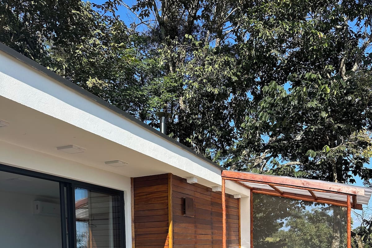 Una terraza moderna al aire libre con un jacuzzi, una mesa de comedor con sillas, y un dormitorio con puerta corrediza de vidrio.