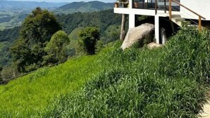 A modern house with a glass facade, situated on a hill with a panoramic view of the landscape. - Pousada Dona Pedra (Córrego do Bom Jesus)