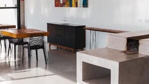 A modern interior with a dining area, a black cabinet, and a colorful abstract painting on the wall. - Pousada Dona Pedra (Córrego do Bom Jesus)