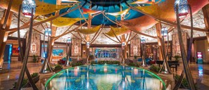 An indoor swimming pool with a central island, surrounded by wooden beams and colorful fabric decorations. - Near Mystic Seaport + On-site Dining, Pool & Spa (Groton)
