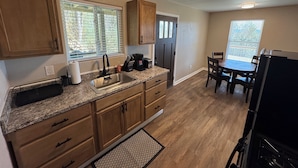 A kitchen with wooden cabinets, a granite countertop, a sink, and a dining area with a table and chairs.