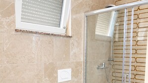 A bathroom with a glass shower enclosure, a bidet, and a toilet. - Studio Apartment Vir 2 (Vir)