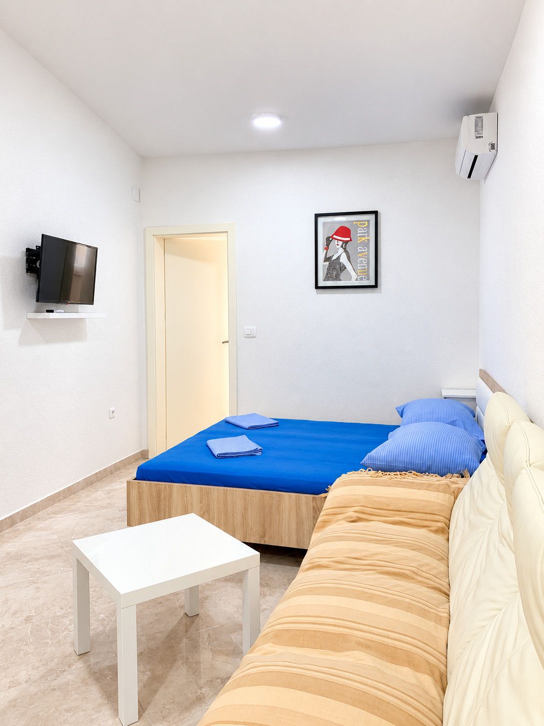 Una camera da letto con un letto, un divano, un tavolino, una TV e una porta.