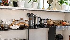A kitchen counter with various utensils, jars, a coffee maker, and a trash bin. - Guesthouse Noestan (Acharistskali)