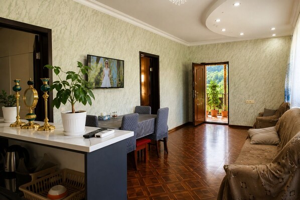 Una sala de estar con comedor, televisión y vistas al exterior.