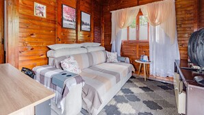 Un accogliente chalet con interni in legno, un divano con cuscini, un tavolino e una ventola.