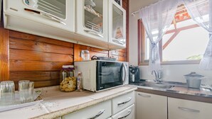 Una cucina con rivestimenti in legno, mobili bianchi, un forno a microonde e un lavello.