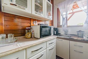 Eine Küche mit Holzwänden, weißen Schränken, einer Mikrowelle und einem Spülbecken.