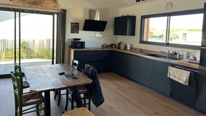 Una cocina moderna con armarios oscuros, una mesa de comedor de madera y un ventanal grande.