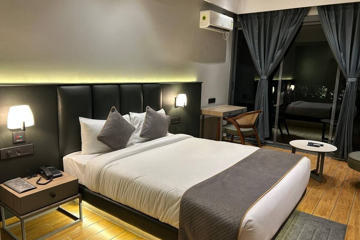 Una habitación de hotel moderna con una cama grande, mesitas de noche, un escritorio y una silla.
