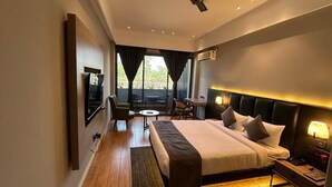 A hotel room with a large bed, a desk, a chair, and a balcony with a view. - COUNTRYSIDE RESORT MURTI (Mal)