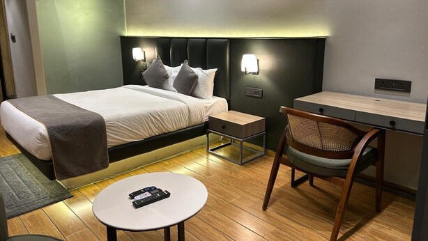 A modern hotel room with a bed, bedside table, chair, and a small desk. - COUNTRYSIDE RESORT MURTI (Mal)