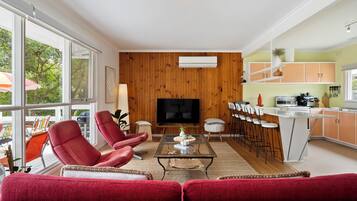 A modern living room with a sofa, chairs, a coffee table, and a TV.